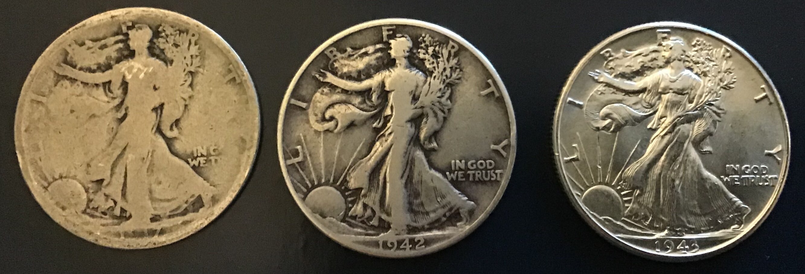 Three Walking Liberty half dollars showing different grades — from left: About Good (AG), Fine (F), and About Uncirculated (AU) — demonstrating how wear progressively reduces design detail across the Sheldon grading scale